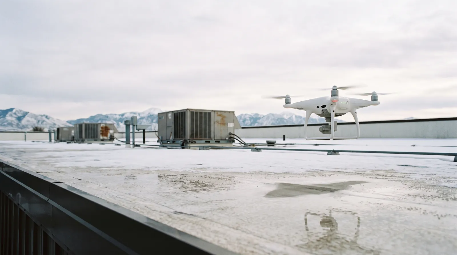 Drone flying over a white-coated commercial flat roof.
