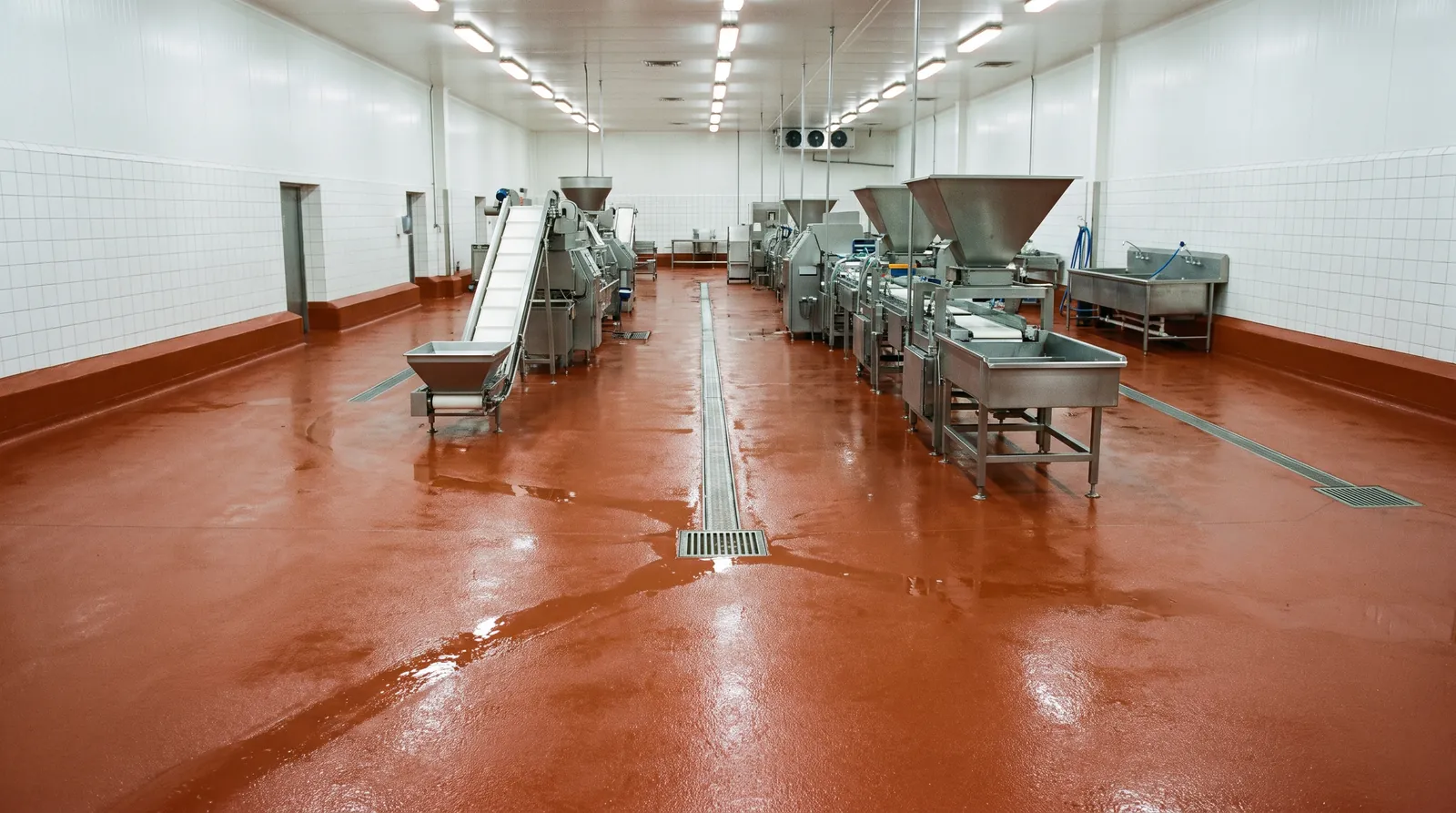 Speckled urethane cement floor with a cove base and trench drain in a food plant.