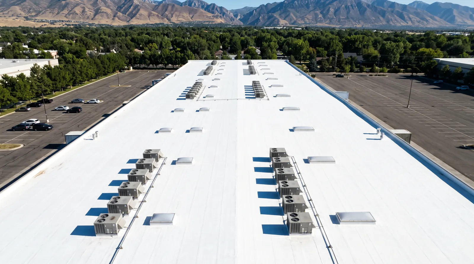 Aerial view of a white-coated commercial flat roof with rooftop equipment.